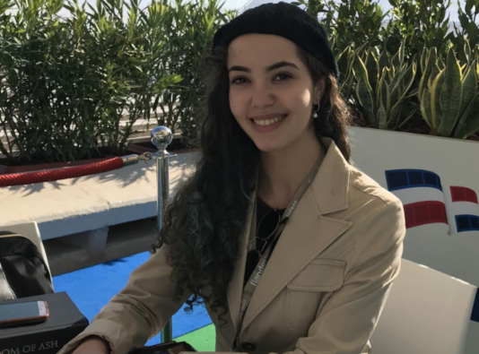 Profile photo of Paula Curry sitting outside at a desk smiling at the camera.