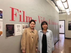Jungyoon Jang & Hae Seoung Kim stand in the hallway of the SVA main building in front of the words "Film - Video & Animation" written on the walls.