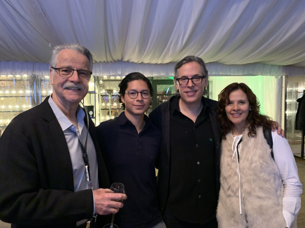 A group of four people stand smiling for a photo at an event. 