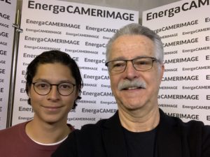 Two people (Alejandro Cortes & Dejan Georgevich) with glasses stand in front of a white fixture with the words EnergaCAMERAIMAGE on it.