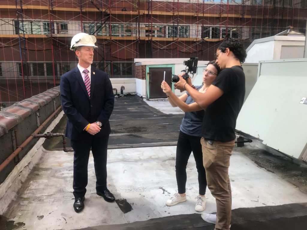 Behind the scenes on Julia Ward's film. She stands with her cameraman in front of an interview subject 