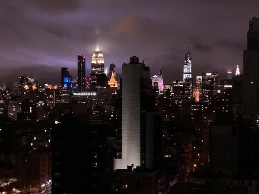 NYC skyline view from the ludlow dorm. The empire state building stands tallest shining bright in the night surrounded by other buildings.