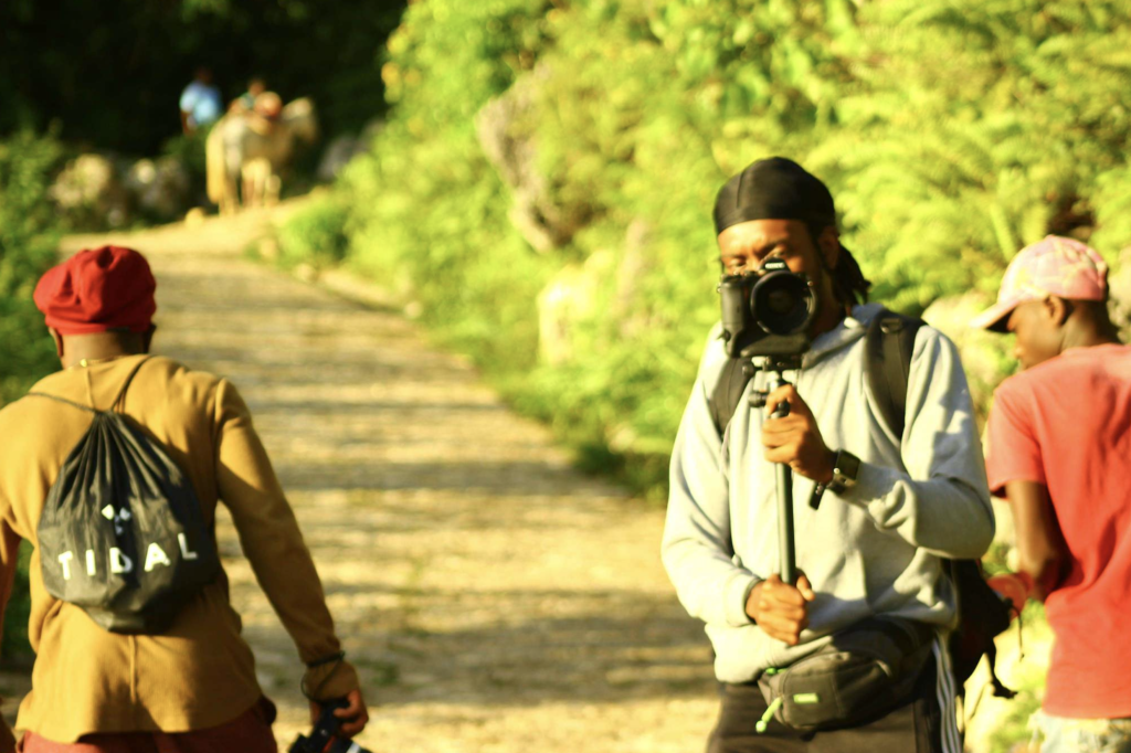 Sage Love stands on a path outside holding a camera 