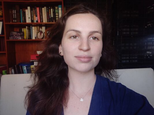 Picture of SVA student Amit Lerner smiling in front of a bookshelf.