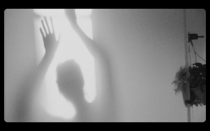 still image from Gonnie Zur's film showing the shadow of a person with their arms raised. Black and white.