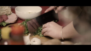 Still from Yoko Chen's short essay film shows a knife cutting and preparing cilantro for the hot pot