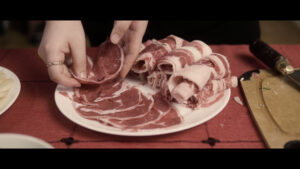 Still from Yoko Chen's short essay film shows slivers of raw meat being prepared for a hotpot