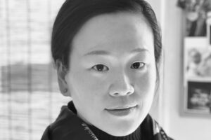 artful Black and white headshot of Kay Hung looking directly into the camera