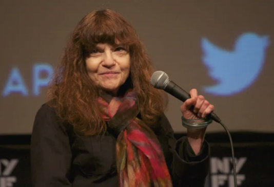 Film Critic Amy Taubin in a medium shot holding a microphone at a panel.