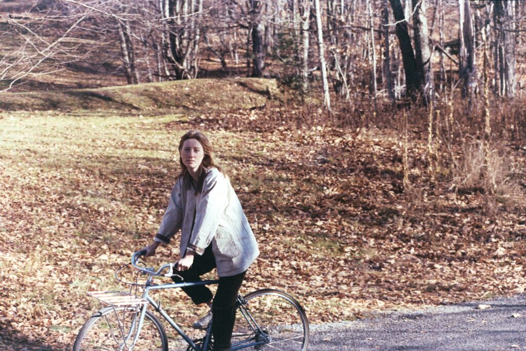 a person rides a bike on a street with fall leaves on the ground behind them