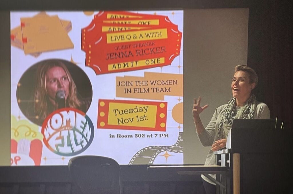 Student stands at podium with Women in Film club info posted behind them.