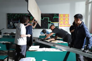behind the scenes photo from Tulpa showing several crew memnbers setting up a shot involving a bounce board in a classroom set.