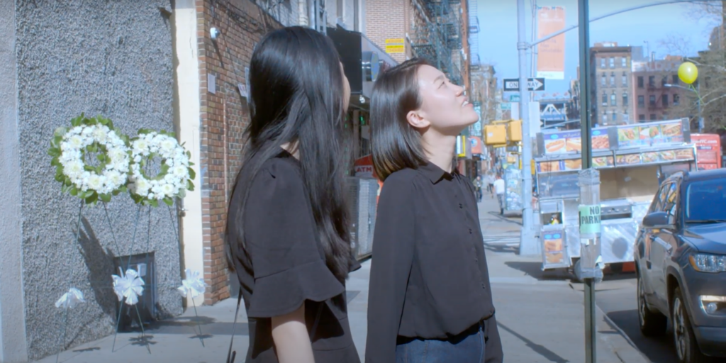 scene from the film showing the two lead characters outside a funeral home looking up at a balloon in the sky.