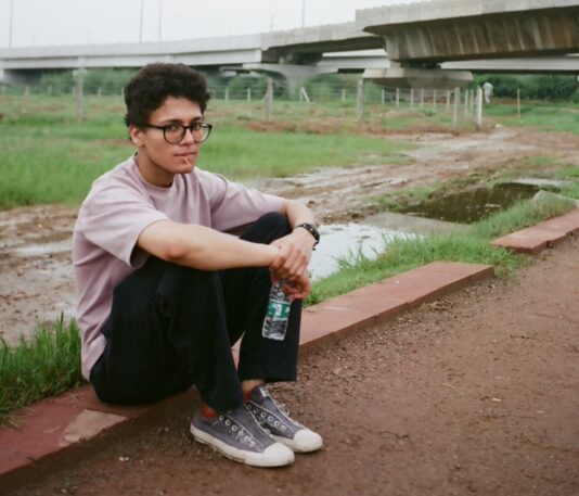 Arnav sits in a field with his feet on the ground.