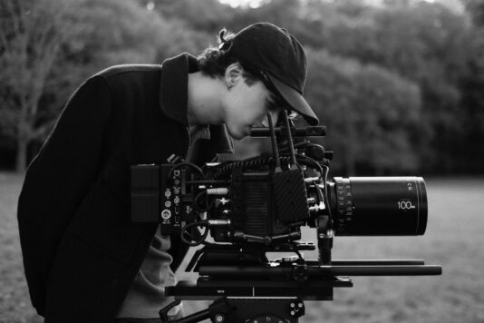 a cinematographer looking through an eye piece of a camera