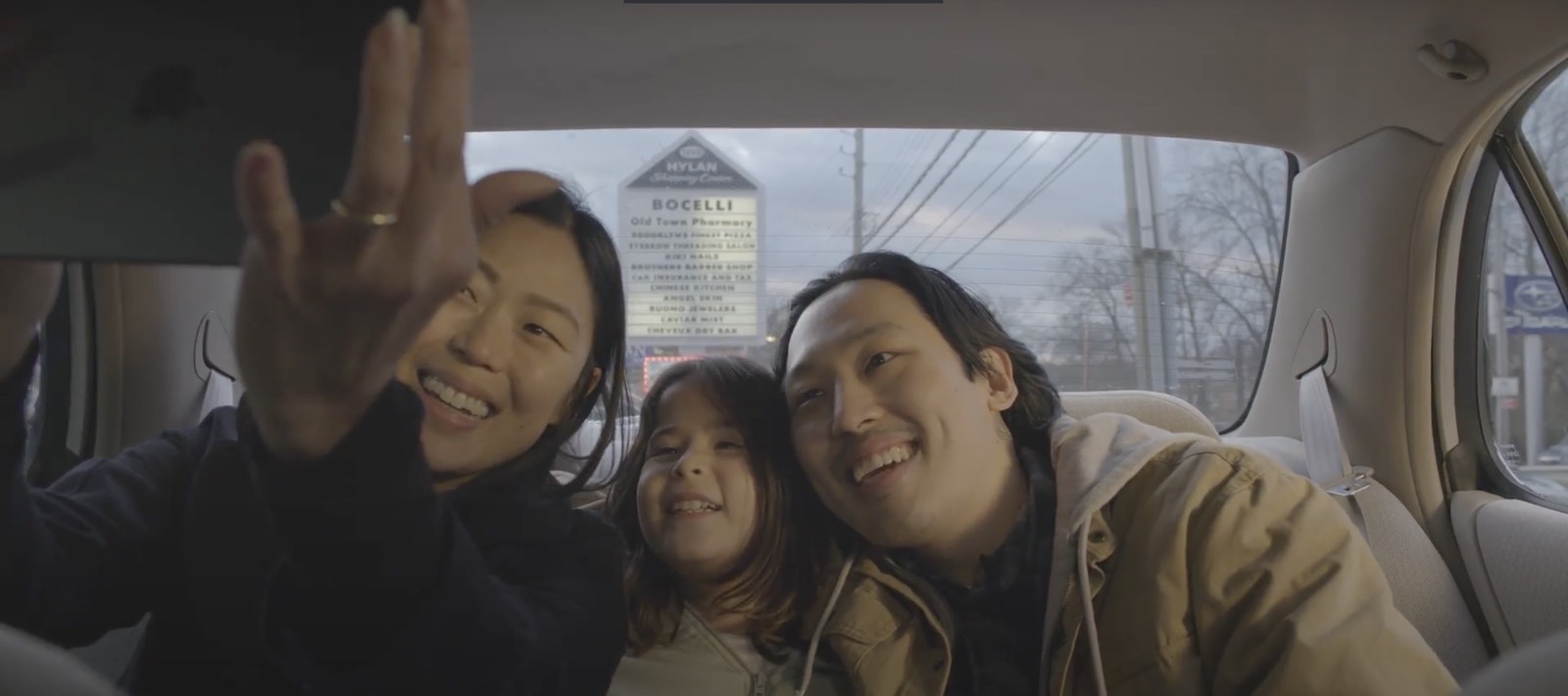 Still image from Alumnus Louis Yeo's film showing the three actors sitting in the back seat of a car taking a selfie