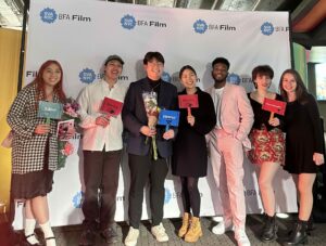 Alumnus Louis Yeo and his crew stand in front of the SVA step and repeat holding flowers and smiling
