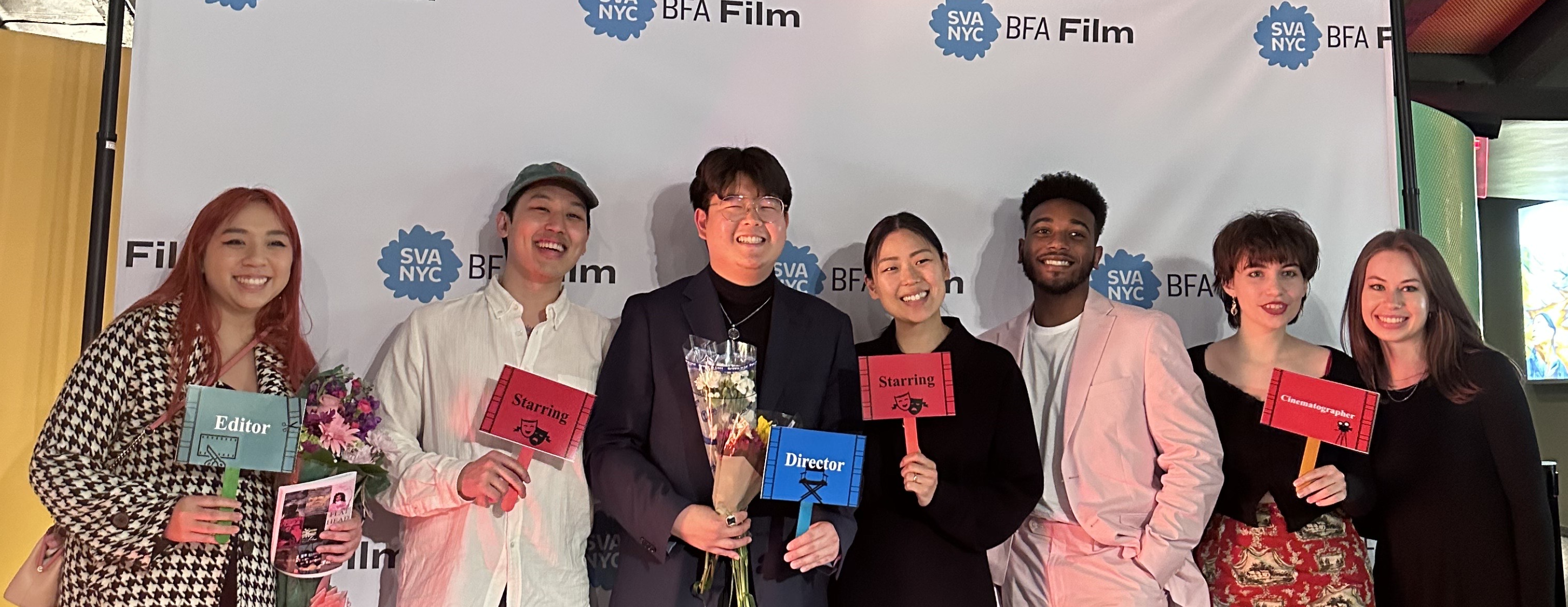 Alumnus Louis Yeo and his crew stand in front of the SVA step and repeat holding flowers and smiling