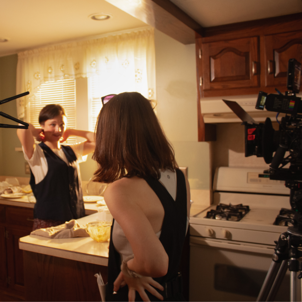 Maura on a kitchen set with crew members preparing a shot.