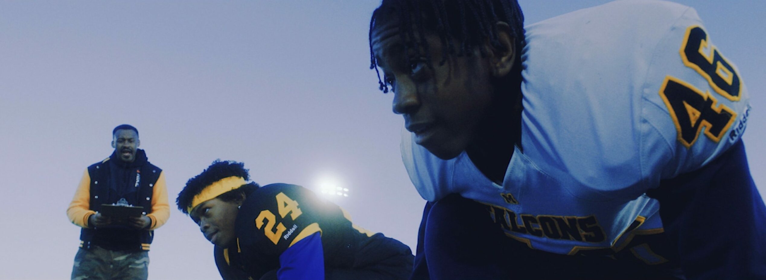 Screenshot from Khalil's film Pass Da Mic shows two actors in a scene wearing football gear and on a football field in closeup.