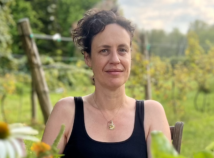 Headshot of faculty member Gina Abatemarco sitting on black tank top at a dinner table outside what appears to be a vineyard