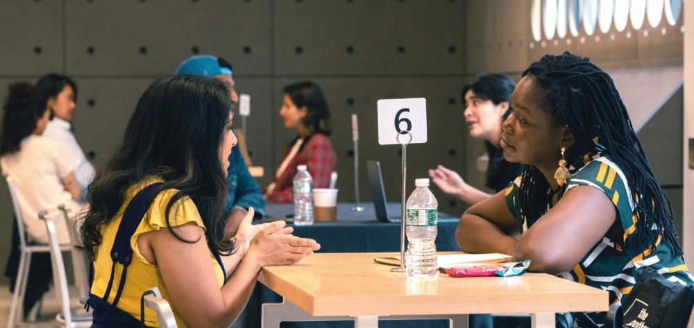 Image of varoius people sitting at a table talking to eachother.