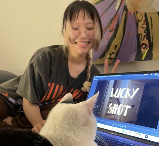 Director Zixia (Jessica) Cheng laughs as her cat appears to use her computer, which displays the film title shot.