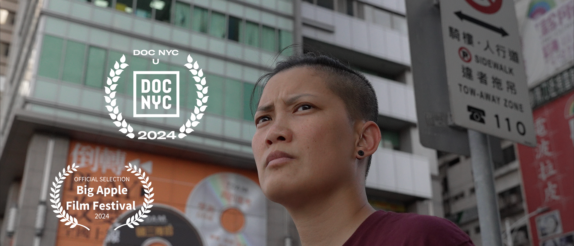 “Find Me’ documentary subject Kuo standing in the middle of the street in Taipei, in front of buildings, ads and street signs in Chinese characters. She looked off into the distance. Two laurels one is DOC NYC U 2024 one is Big Apple Film Festival 2024 official selection.