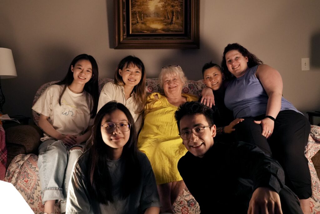 Five crew members and the two documentary subjects all sit on a sofa posing for the picture