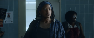 Still image from Annie's film Home Coming, shows the protagonist a young high school student standing in the school hallway with a look of shock on their face.