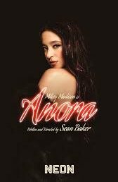 Poster for the film Anora. Mikey Madison in character against a black background, behind the title in red neon cursive font. 